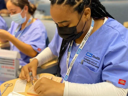 Harmony Taylor from the Turner-UCLA Allied Health Internship Program in Summer 2022 practicing surgical technician tasks including a mock suturing exercise.